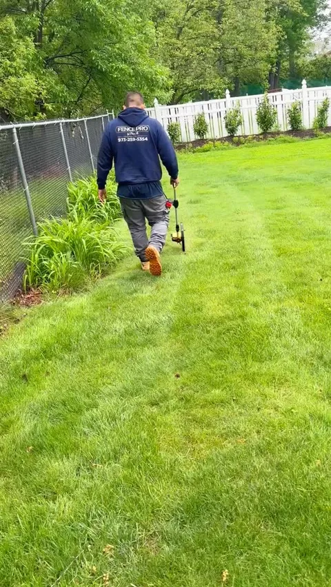 Fence Pro by Bruno crew member walking alongside a chain link fence