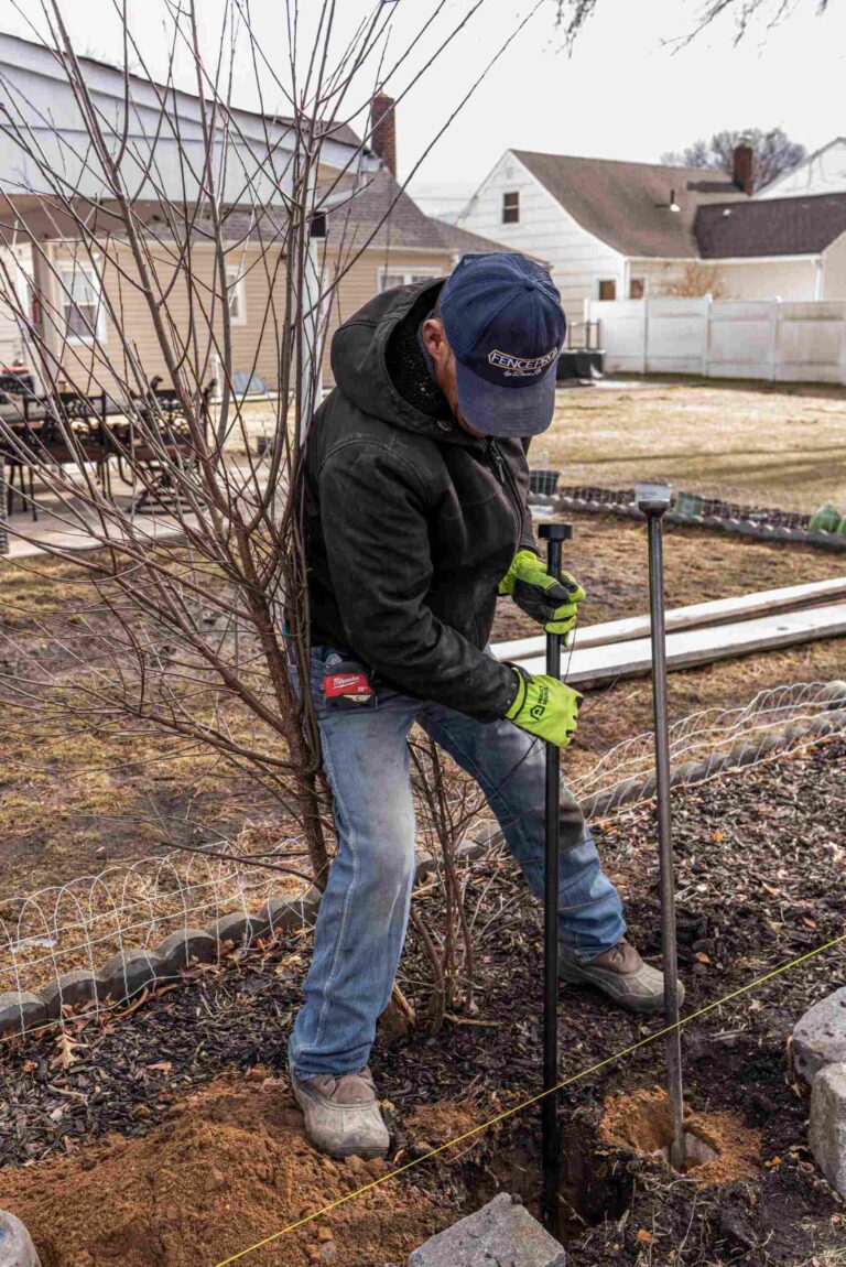 Bruno Facundo installing a fence post at a backyard project in Wayne, New Jersey