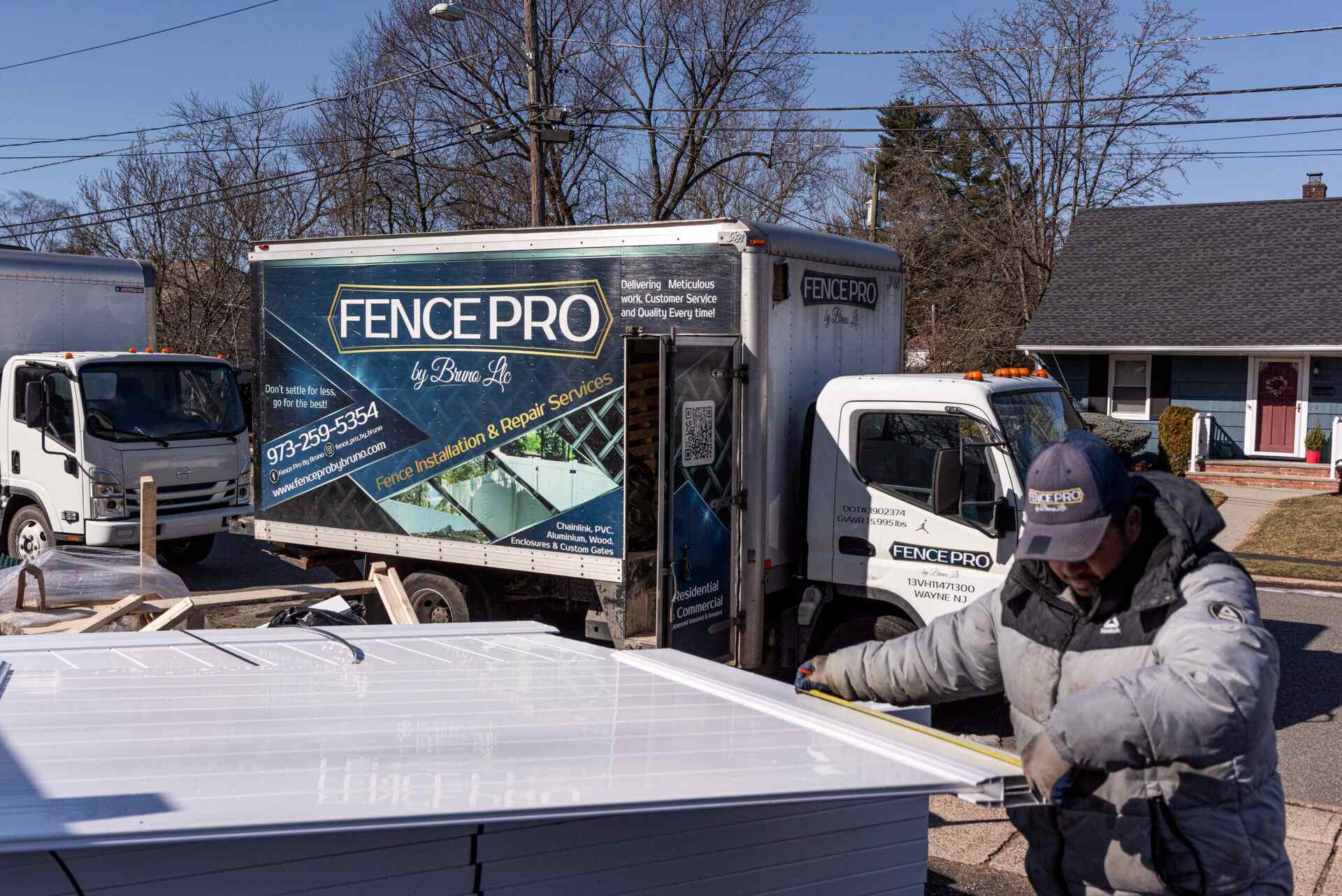 Fence Pro installer carrying a vinyl panel from the company box truck to the install site