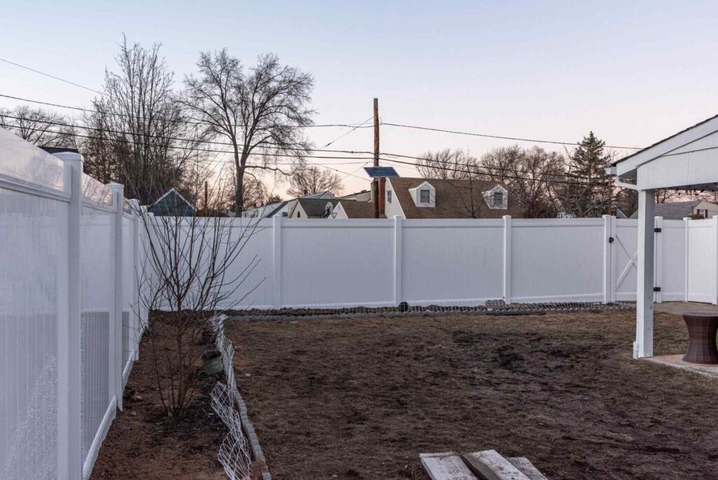 Completed white vinyl privacy fence at dusk in a residential New Jersey backyard